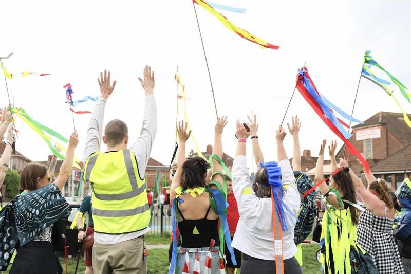 group of people with backs to camera and hand in the air