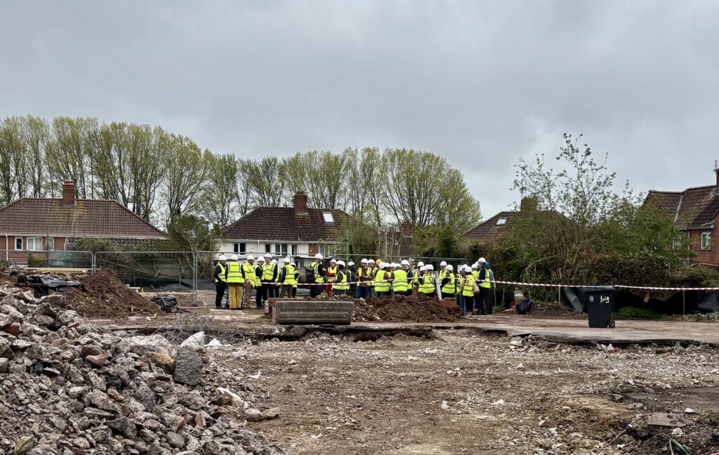 a group of several people in high vis amongst rubble on a building site